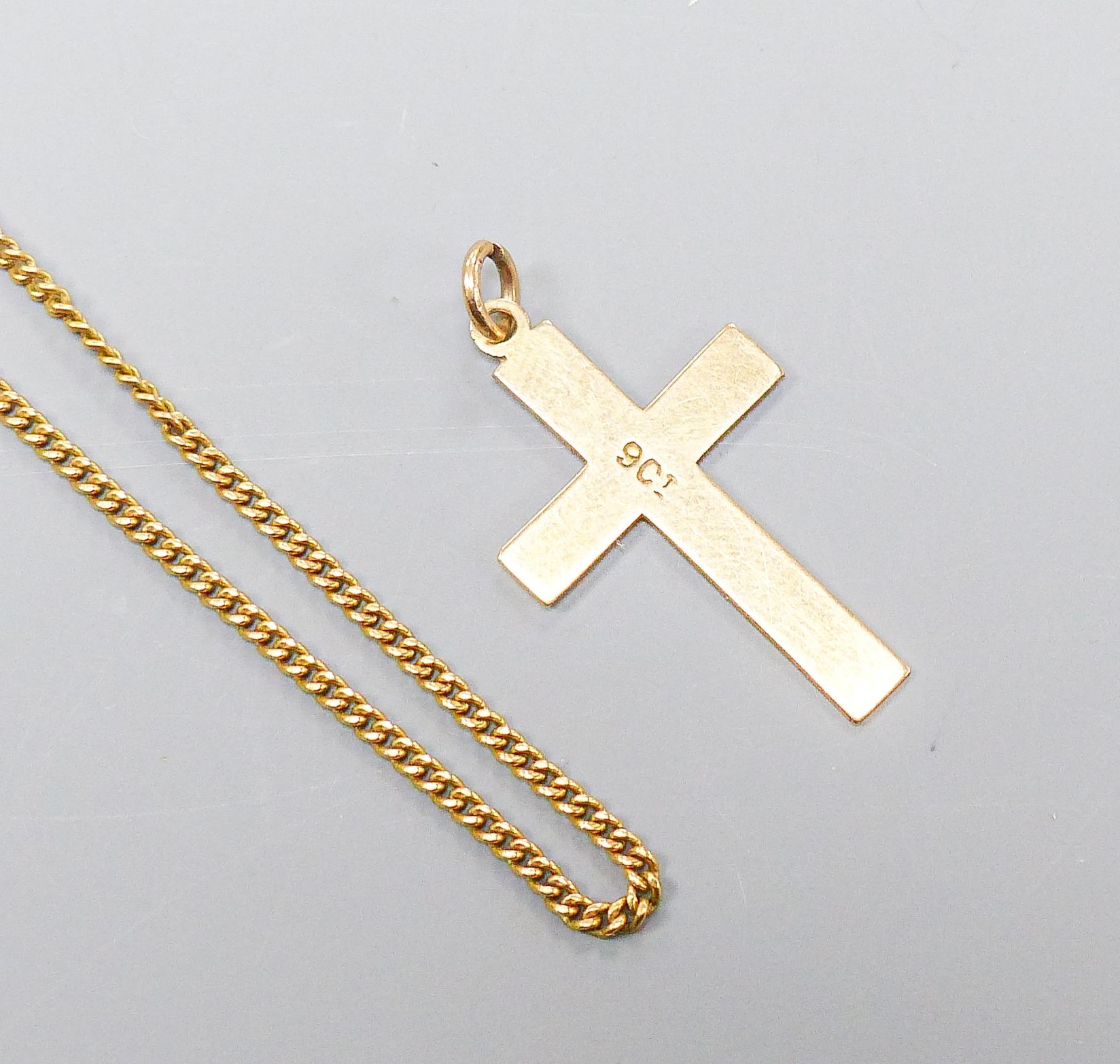 An 18ct yellow gold fine curb-link necklet, 51cm, 5 grams and a 9ct crucifix, 0.8 grams.